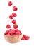 Fresh ripe tasty raspberries falling into bowl on background