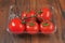 Fresh and ripe tomatoes on a vine in a plastic container on a wooden table surface, Fresh produce product