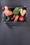 Fresh ripe ugly vegetables in plastic box on dark grey background.