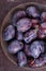 Fresh ripe whole purple damson plums on wooden plate