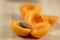 Fresh ripened apricots cut in halves with stone on wooden table in sunlight, edible tasty fruits ripening in early summer