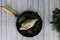 Fresh river fish bream on black cast frying pan, dill, laurel leaf, thyme, oregano, coriander.