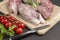 Fresh river fish on cutting board. Branch of cherry tomato on table. Black background. View from above