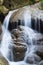 Fresh river water flows from a small waterfall that form two rocks