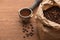 Fresh roasted coffee beans in paper bag and ground coffee in filter holder on wooden table.