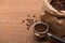 Fresh roasted coffee beans in paper bag and ground coffee in filter holder on wooden table.