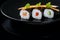 Fresh rolls on a plate, roll with salmon, cucumber and pepper served with carrot slices and parsley, black background