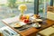 Fresh romantic breakfast table next to morning briliant light window, with coffee cup, bread, fruit, juice, egg