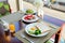 Fresh romantic breakfast table next to window with bread, fruit, juice, milk, egg, vegetable