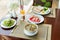 Fresh romantic breakfast table next to window with bread, fruit, juice, milk, noodle soup