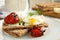 Fresh rye crispbreads with poached egg, cheese and grilled tomatoes on plate, closeup