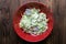 Fresh salad of autumn vegetables - green cabbage, cucumber, purple onions, parsley - in a red bowl on rustic wooden table. Rich