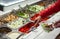 Fresh Salad bar counter with person`s hands lifting vegetable into a salad bowl.