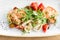 Fresh Salad with calamari, mushrooms, tomatoes and fried potato on wooden background. Seafood salad. Mediterranean