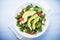 Fresh salad with chicken, tomatoes, spinach and avocado on blue wooden background top view