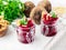 Fresh salad of grated boiled beetroot in glass jars, white wooden background, side view.