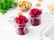 Fresh salad of grated boiled beetroot in jars, white wooden background, side view.