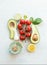 Fresh salad ingredients : halves avocado, tomatoes, lemon and olives oil on a white background. Top view. Vegetarian food. Healthy