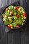 Fresh salad of spinach, lupine beans, tomatoes and olives close-up in a plate. vertical top view