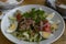 Fresh salad with tuna, eggs, lettuce, red onions and herbs in a deep white plate. Vegetarian option. A healthy, green and vitamin-