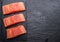 Fresh salmon fillets on black cutting board