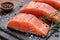 Fresh salmon fillets on black cutting board with herbs and spices