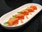 Fresh salmon roll with asparagus and cucumber topped with salmon roe sauce in white plate