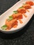 Fresh salmon roll with asparagus and cucumber topped with salmon roe sauce in white plate