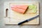 Fresh salmon with skin, lemon slice, fork ,tongs and knife on wood chopping board.