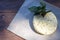 Fresh salted Levantine halloumi cheese and a sprig of basil on a brown wooden background.