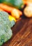 Fresh salubrious colourful vegetables on wooden background, broccoli in focus, potatoes, carrots, zucchini unfocused, selected