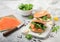 Fresh sandwiches with bagel and salmon, cream cheese and wild rocket on white board with smoked salmon pack and knife