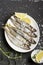 Fresh sea fish smelt or sardines ready for cooking with lemon, thyme, rosemary and coarse sea salt. The concept of fresh