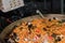 Fresh seafood penne tomato pasta cooking in large wok pan during hotel brunch buffet outside