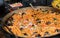 Fresh seafood penne tomato pasta cooking in large wok pan during hotel brunch buffet outside