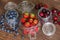 Fresh seasonal fruits in jars / blueberries, strawberries and cherries on a wooden table