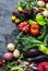 Fresh seasonal vegetables food background. Aubergines, tomatoes, radishes, peppers, broccoli, potatoes, beets on a dark background