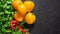 Fresh seasonal vegetables: yellow tomatoes, parsley, basil, red chili pepper on black background. Top view. Copy space