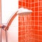 Fresh shower where Water running from shower head and faucet in modern bathroom with orange wall