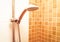 Fresh shower where Water running from shower head and faucet in modern bathroom with orange wall