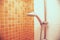 Fresh shower where Water running from shower head and faucet in modern bathroom with orange wall