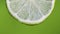 Fresh slice lime, a drop of water falls. The fruit gives off freshness and juice filling. Green background