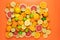 Fresh sliced, halved and whole citrus fruits almost completely cover an orange background
