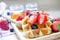 Fresh sliced organic strawberry fruit on delicious homemade waffle with blueberry on wooden plate