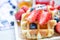 Fresh sliced organic strawberry fruit on delicious homemade waffle with blueberry on wooden plate