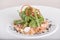 Fresh smoked salmon salad,  served with rucola and baby spinach and pieces of vegetables,  decorated with herbs,  placed on white