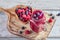 Fresh smoothies in a glass jar with ripe raspberries and blueberries in a wooden heart-shaped bowl on rustic cutting board