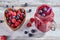 Fresh smoothies in a glass jar with ripe raspberries and blueberries in a wooden heart-shaped bowl on rustic white table