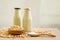 Fresh soybean seeds in brown wooden bowl with sugar in spoon and two bottles of soy milk on the table