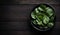 Fresh Spinach in a Black Bowl on a Wooden Table, Copy Space